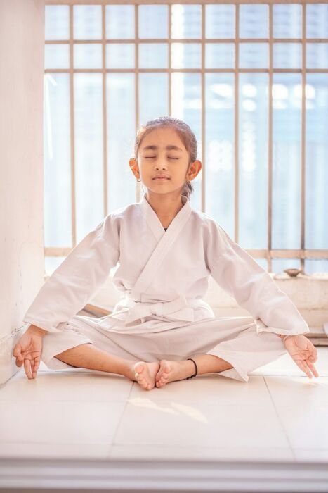 Young girl meditating cross-legged with eyes closed