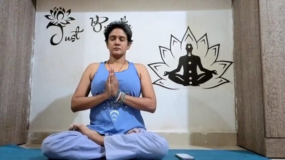 Nitya seated with hands in namaste
